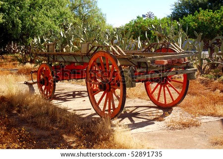 An old traditional Voortrekker wagon standing in front of a cactus bush on a South African farm during drought in summertime