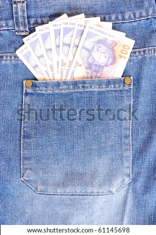 A back pocket of a blue jeans full of one hundred notes of South African currency, Rands.