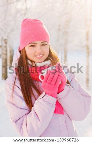 Young woman with a cup of hot drink in winter park