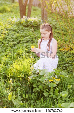 smiling girl wonders on flower, tearing petals
