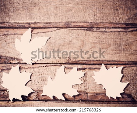 wooden background with paper leaves