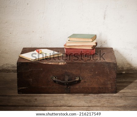 Vintage old suitcase with old books on floor