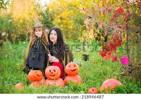mother and daughter with pumpkins dressed as witches outdoor