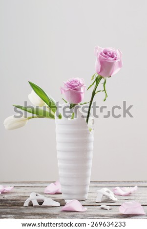 pink roses in broken  vase on old wooden table