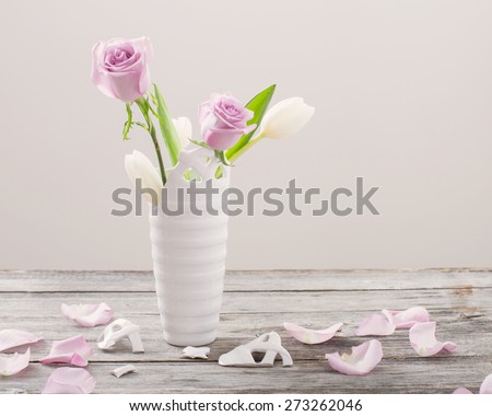 pink roses in broken vase on old wooden table
