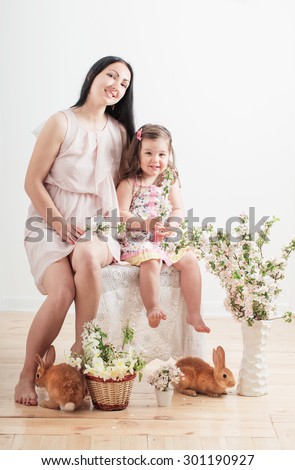 little girl and  mother with rabbits indoor