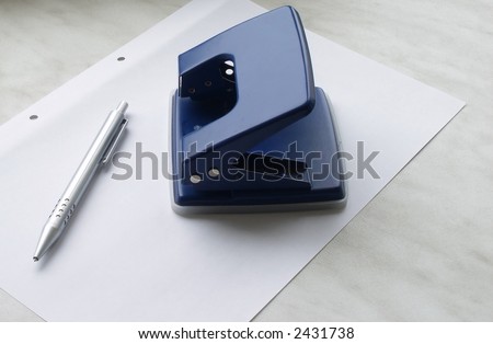 Puncher and pen laying on a sheet of a white paper