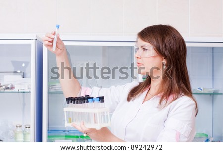 woman in lab coat with chemical glassware