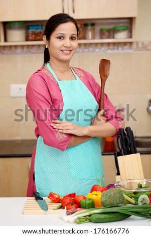 Confident young Indian woman with kitchen utensil