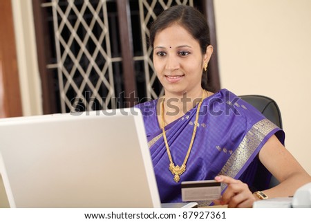 Beautiful traditional woman sitting at home and shopping with laptop