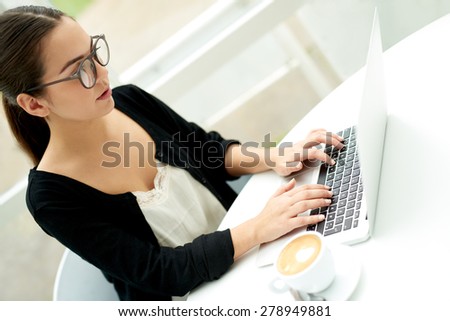 Young businesswoman using her laptop computer as she works from home sitting on her patio at a table typing on the keyboard, closeup view