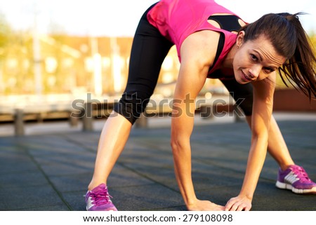 Woman doing a full body stretch outside  leaning forward to touch floor and smiling.