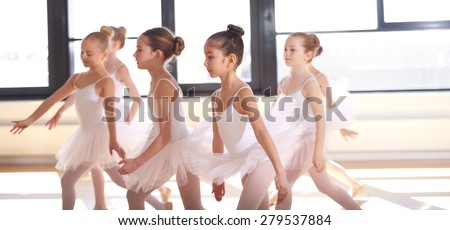 Group of young ballerinas performing a choreographed ballet as they train together at a ballet studio