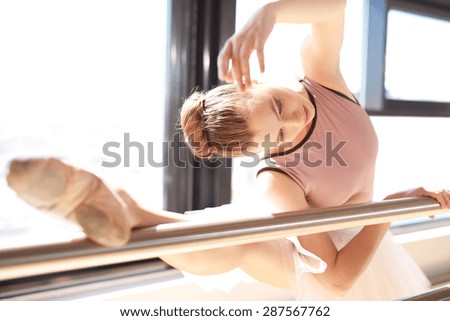 Close Up of Young Ballerina Stretching at Barre in Sunny Dance Studio