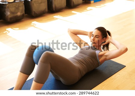 Fit woman is doing sit ups with medicine ball between her legs