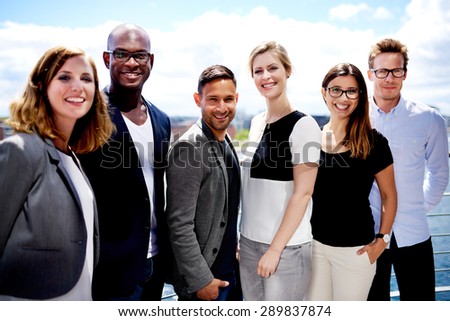 Group of executives smiling and posing outside for picture.