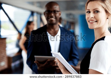Black male executive and white female executive standing together and smiling at camera