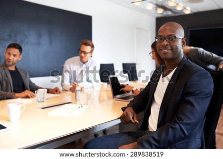 Young black male executive smiling and facing camera during work meeting