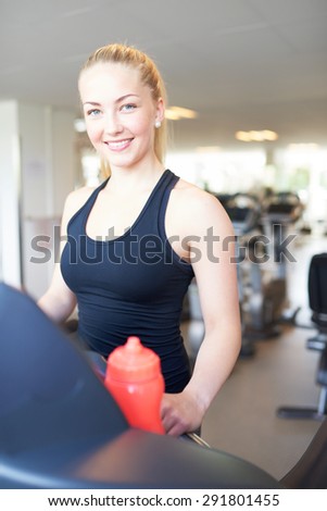 Close up Cheerful Fit Young Woman in Black Sleeveless Shirt, Exercising on Treadmill Machine Inside the Gym, Smiling at the Camera