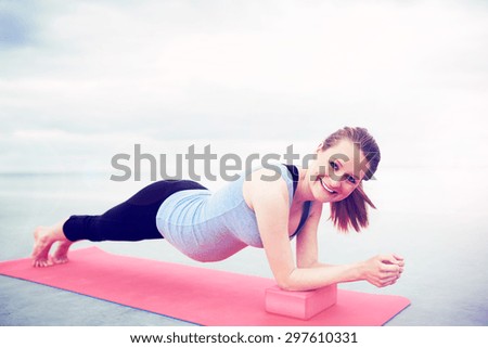 Pretty pregnant woman with a happy smile working out on a gym mat doing press-ups and stretching exercises to strengthen her abdominal muscles