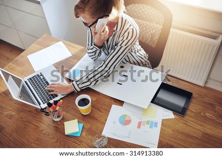 Successful businesswoman with an e-business working from an office at home telemarketing and taking orders over the phone or consulting with clients, high angle view