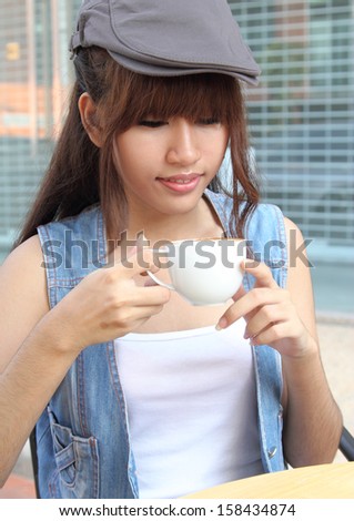 Image of young asian woman holding hot coffee on her hand at coffee shop