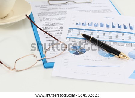 image of graphics and finance report for business with pen and glasses