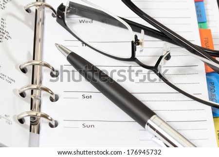 closeup image of pen glasses and organizer book