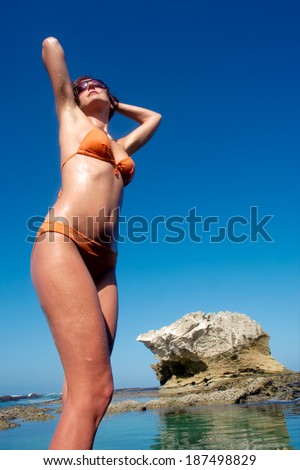 Happy young woman sunbathes on awesome rocky beach. Shot in De Hoop Nature Reserve, Western Cape, South Africa.