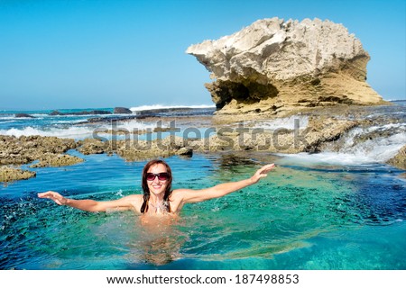 Happy young woman splashes in water on awesome rocky beach. Shot in De Hoop Nature Reserve, Western Cape, South Africa.