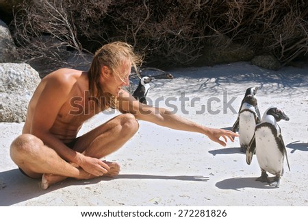Young man communicates with penguins. Shot in the Boulders Beach Nature Reserve, near Cape Town, Western Cape, South Africa.