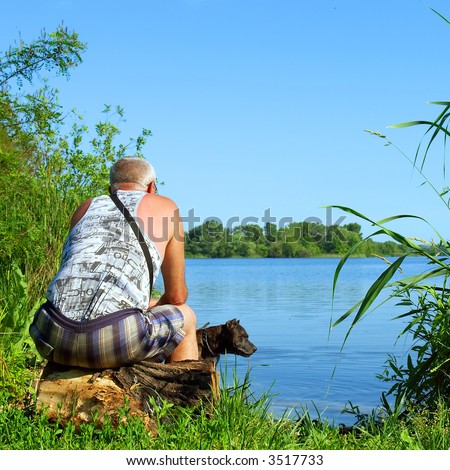 Two thinkers - old man and dog on river shore in morning. Shot in June near Dnieper river, Ukraine.