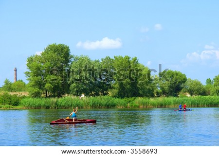Boy in canoe races after two men on river in morning. Shot in June, near Dnieper river, Ukraine.