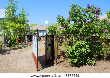 Gate into country homestead and bush of lilac nearby. Shot in Ukraine.