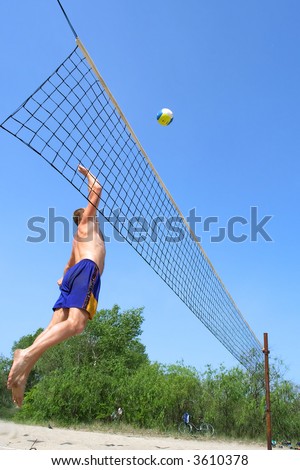 People playing beach volleyball - fat man jumps high to strike the ball. Shot near Dnieper river, Ukraine.