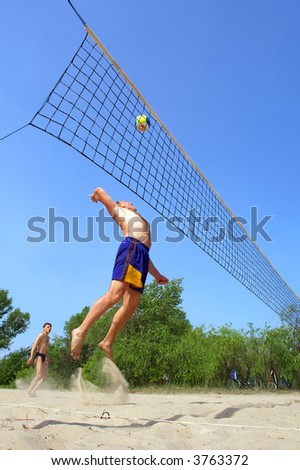 Playing beach volleyball - fat man jumps high to spike the ball. Shot near Dnieper river, Ukraine.