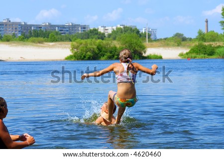 Kids play in water - teen girl jumps up from boy\'s shoulders. Shot in June, near Dnieper river, Ukraine.