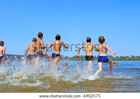Group of teens run into water in hot summer day. Shot in June, near Dnieper river (Dniepropetrovsk, Ukraine).