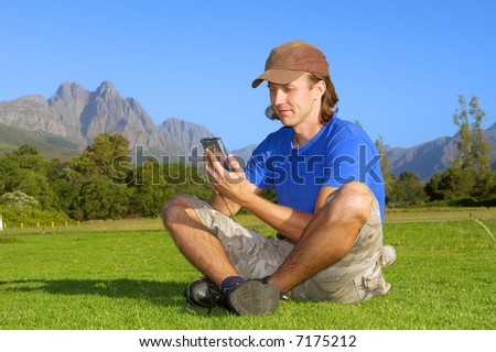 Relaxed man sits in lotus pose and looks into pda - and misty mountains are background. Shot in Stellenbosch, South Africa.