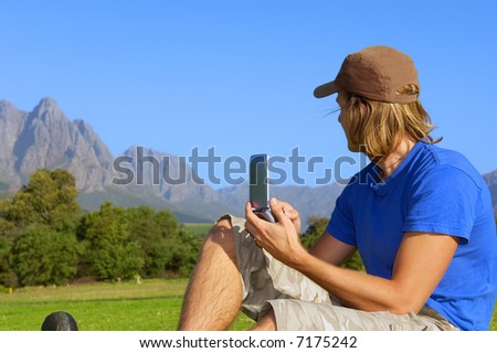 Man with smartphone/pda/gps looks at misty mountains. Shot in Stellenbosch, South Africa.