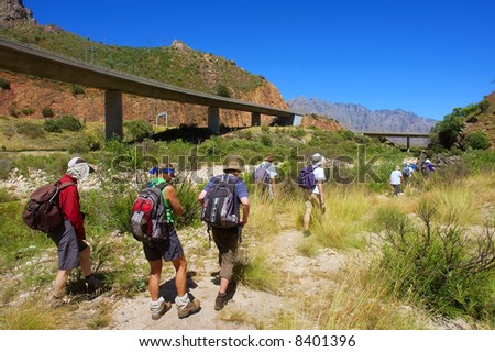 Three female hikers follow the group walking towards bridge in awesome mountains. Shot in the Kromrivier - Du Toitskloof Nature Reserve, near Paarl, Western Cape, South Africa.