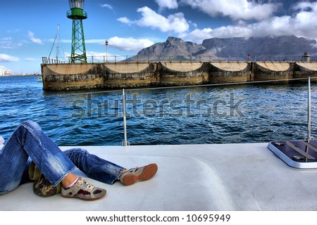 Legs in jeans in front of Table Mountain and pier. Shot near Waterfront, Cape Town, Western Cape, South Africa.