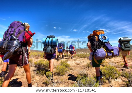 Group of hikers walks in savanna - low-angle view. Shot in the Langeberge highlands near Grootrivier and Gouritsrivier rivers crossing, Garden Route, Western Cape, South Africa.
