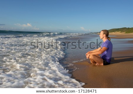 Young man meditates on beach in lotus pose - sunrise light. Shot in Sodwana Bay Nature Reserve, KwaZulu-Natal province, Southern Mozambique area, South Africa.