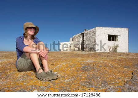 Woman sitting next to abandoned house next to sea. Shot in West Coast Nature Reserve, near Langebaan, Western Cape, South Africa.