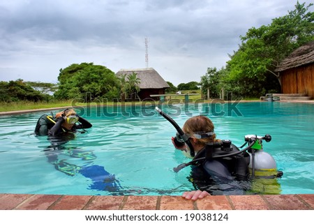 Two divers in training pool under storm skies. Shot in Sodwana Bay, KwaZulu-Natal province, Southern Mozambique area, South Africa.