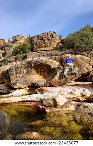 Man climbs on rocks from river. Shot in Gifberg Mountains, near Wanrhynsdorp, Western Cape, South Africa.