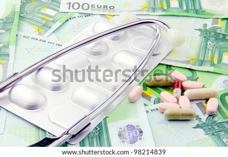 Health care is expensive today; pills, stethoscope and paper money for background.