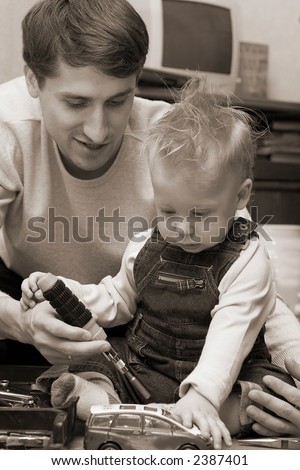 Father playing with his son in car repair and teaching him how to use screwdriver. Black and white photo