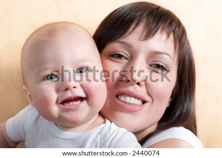 young mother and her little baby, both smiling. Focus is on the kid\'s face, mother is little out of focus.